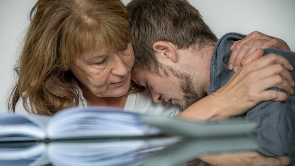 Eine Mutter nimmt ihren ängstlichen Sohn in die Arme.